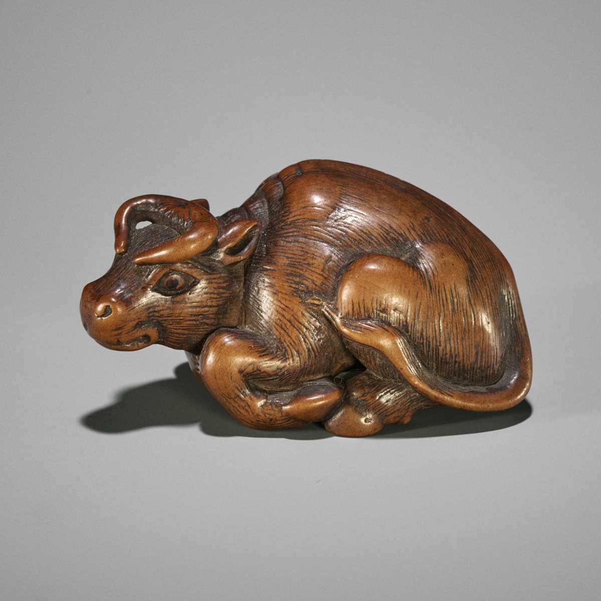 KOKEI: A WOOD NETSUKE OF A RECUMBENT OX