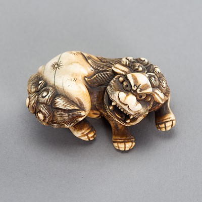 Lot 1615 - AN IVORY NETSUKE OF A RECLINING SHISHI