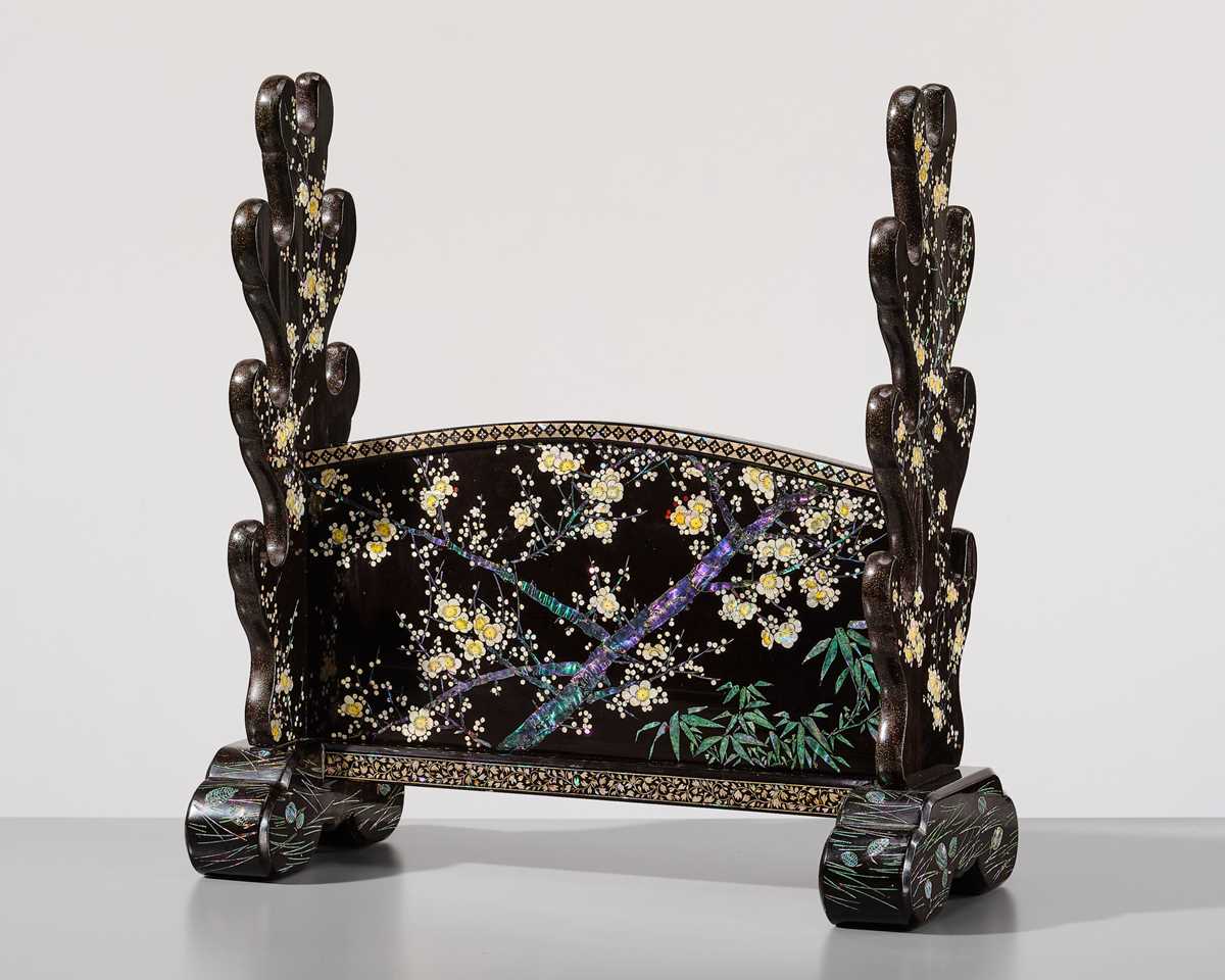 Lot 135 - A SUPERB MOTHER-OF-PEARL INLAID AND BLACK-LACQUERED ‘THREE FRIENDS OF WINTER (SHOCHIKUBAI)’ KATANA-KAKE (SWORD STAND)