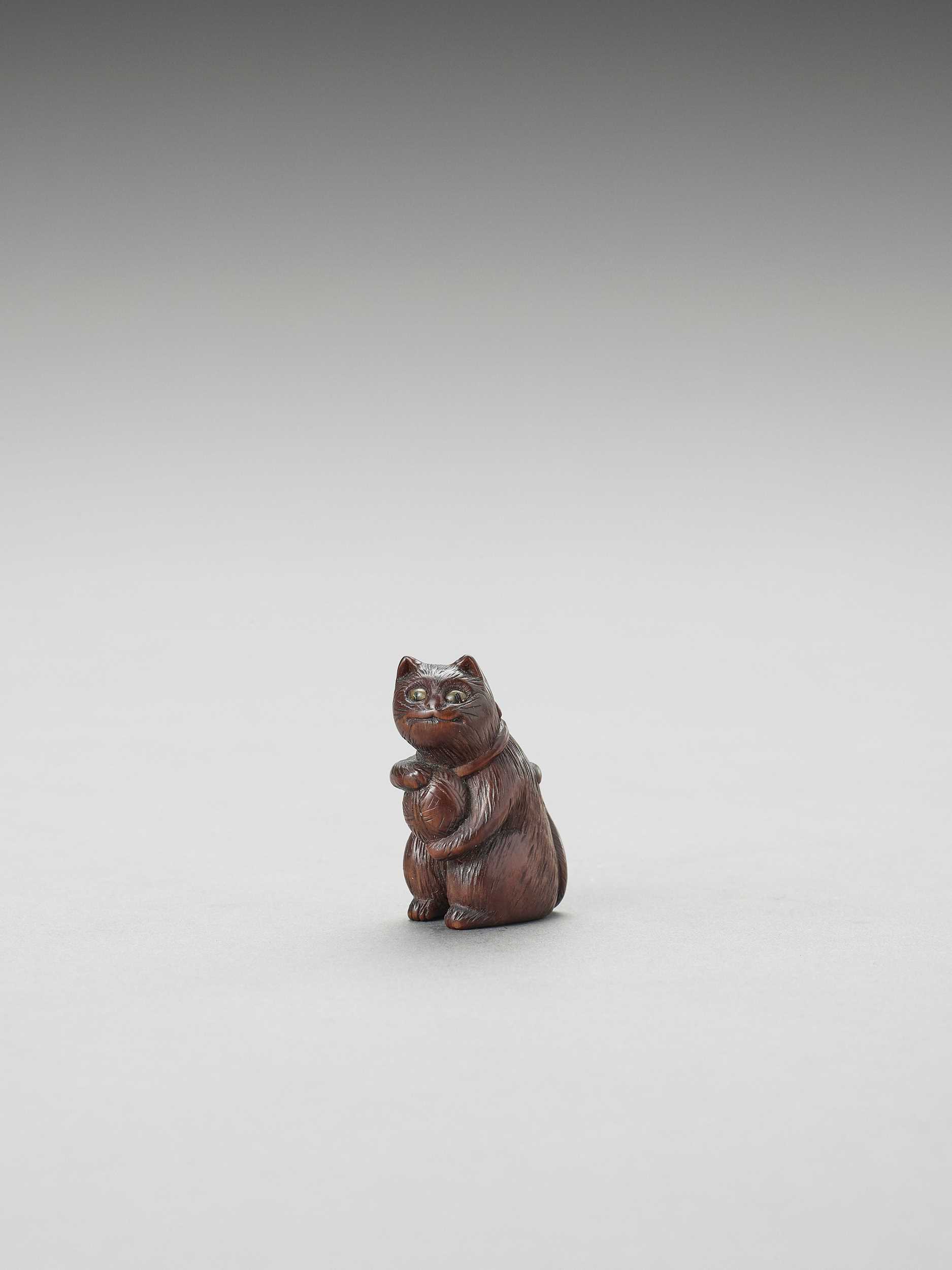 Lot 323 - A CHARMING TOKYO SCHOOL WOOD NETSUKE OF A CAT WITH A BALL