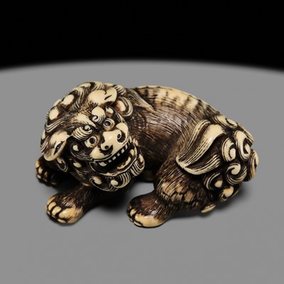 Lot 105 - A POWERFUL IVORY NETSUKE OF A RECLINING SHISHI, ATTRIBUTED TO MITSUHARU