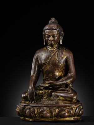Lot 12 - AN INCSCRIBED GILT-COPPER FIGURE OF BUDDHA SHAKYAMUNI, NEPAL, LATE 13TH-EARLY 14TH CENTURY
