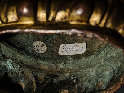 Lot 12 - AN INCSCRIBED GILT-COPPER FIGURE OF BUDDHA SHAKYAMUNI, NEPAL, LATE 13TH-EARLY 14TH CENTURY