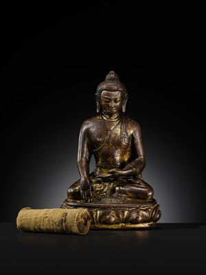 Lot 12 - AN INCSCRIBED GILT-COPPER FIGURE OF BUDDHA SHAKYAMUNI, NEPAL, LATE 13TH-EARLY 14TH CENTURY