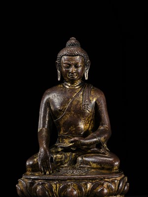 Lot 12 - AN INCSCRIBED GILT-COPPER FIGURE OF BUDDHA SHAKYAMUNI, NEPAL, LATE 13TH-EARLY 14TH CENTURY