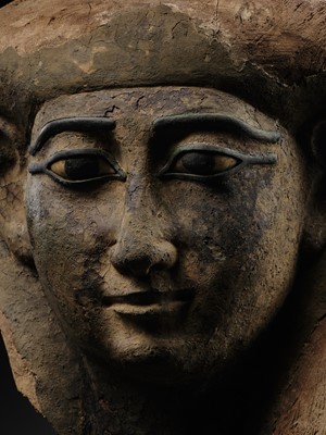 Lot 14 - A BRONZE AND LIMESTONE INLAID WOOD SARCOPHAGUS MASK, PTOLEMAIC PERIOD