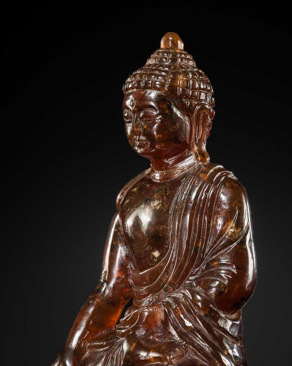 Lot 102 - A RARE AMBER FIGURE OF BUDDHA SHAKYAMUNI, EARLY QING DYNASTY