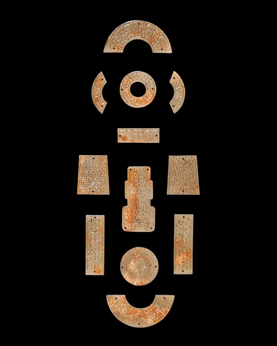 Lot 87 - A SET OF TWELVE WHITE AND RUSSET JADE ORNAMENTS, EASTERN ZHOU DYNASTY