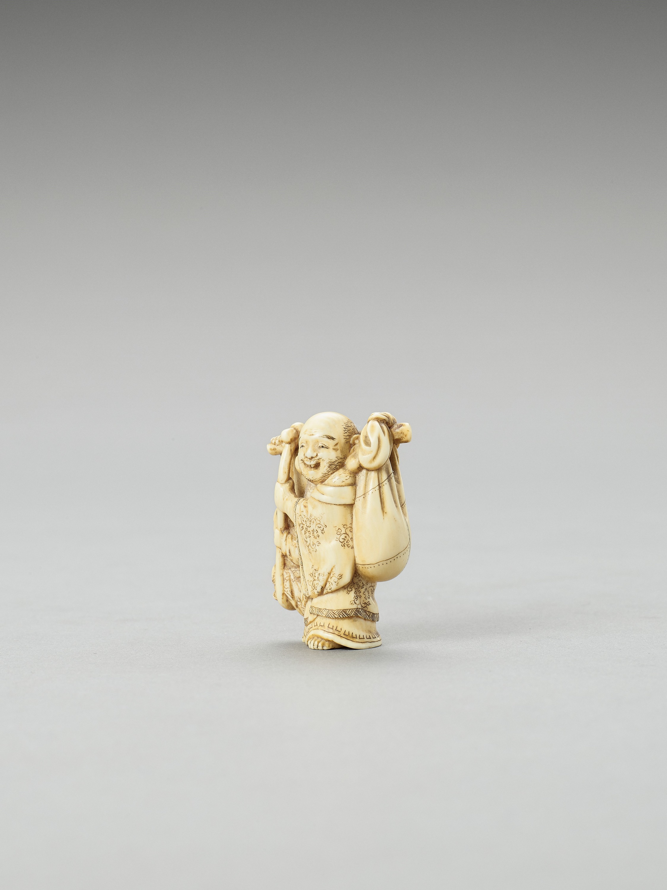 Lot 208 - TOMOAKI: AN IVORY NETSUKE OF HOTEI CARRYING