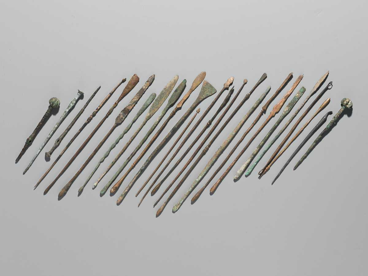 Lot 174 - A GROUP OF TWENTY-FIVE GREEK AND ROMAN BRONZE PINS, SPOONS AND TOOLS, 1ST MILLENNIUM AD AND EARLIER