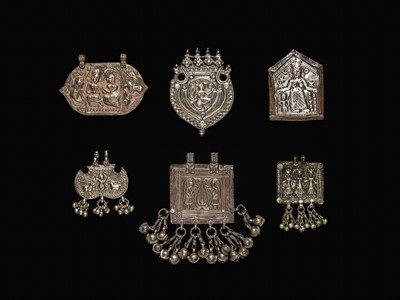 Lot 204 - A GROUP OF SIX SILVER REPOUSSÉ AMULET PENDANTS AND VOTIVE PLAQUE, HIMACHAL PRADESH AND RAJASTHAN