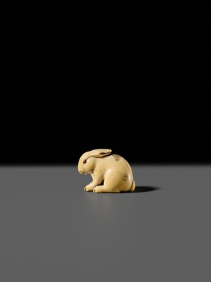 Lot 120 - RANICHI: A FINE IVORY NETSUKE OF A PIEBALD HARE WITH AMBER EYES
