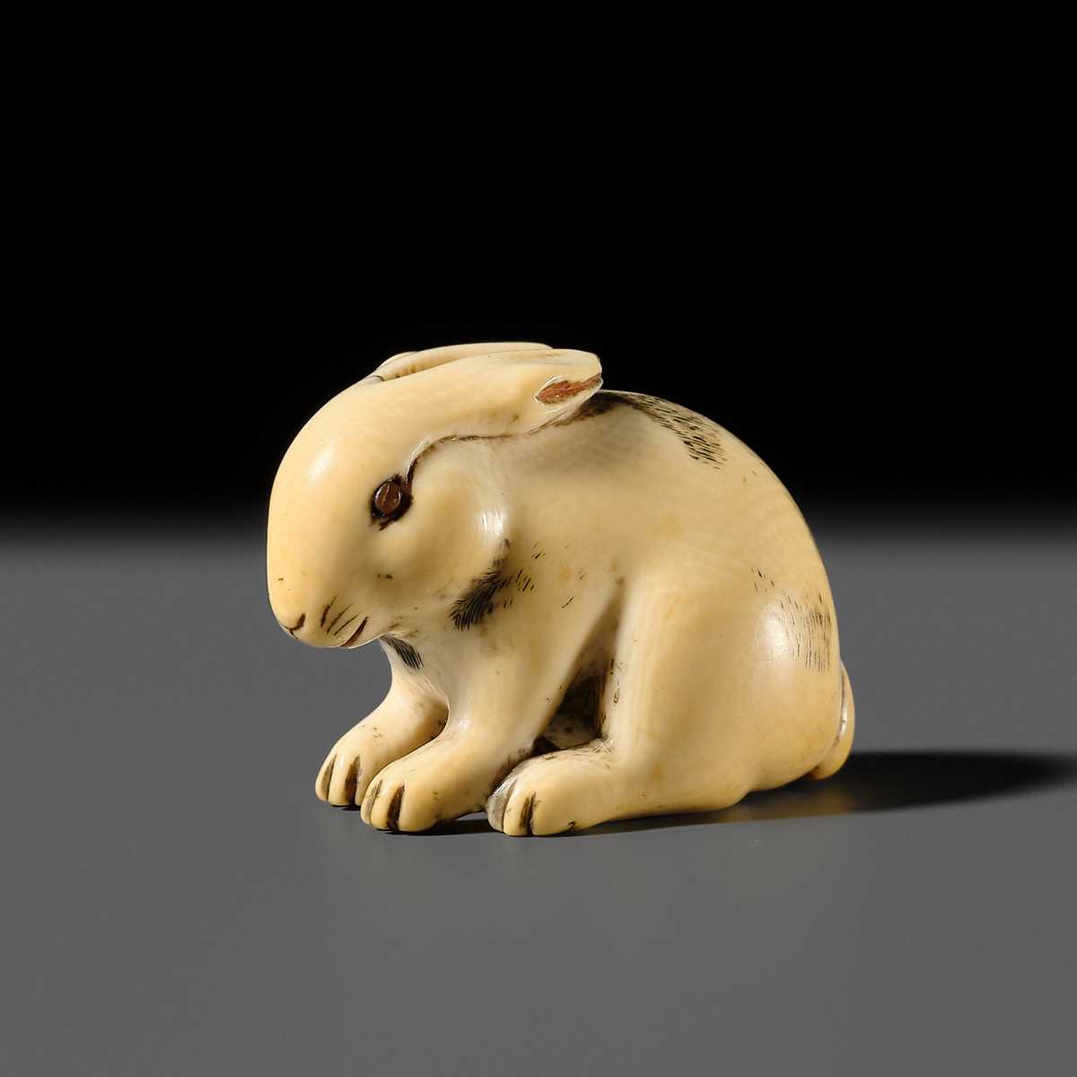 Lot 120 - RANICHI: A FINE IVORY NETSUKE OF A PIEBALD HARE WITH AMBER EYES