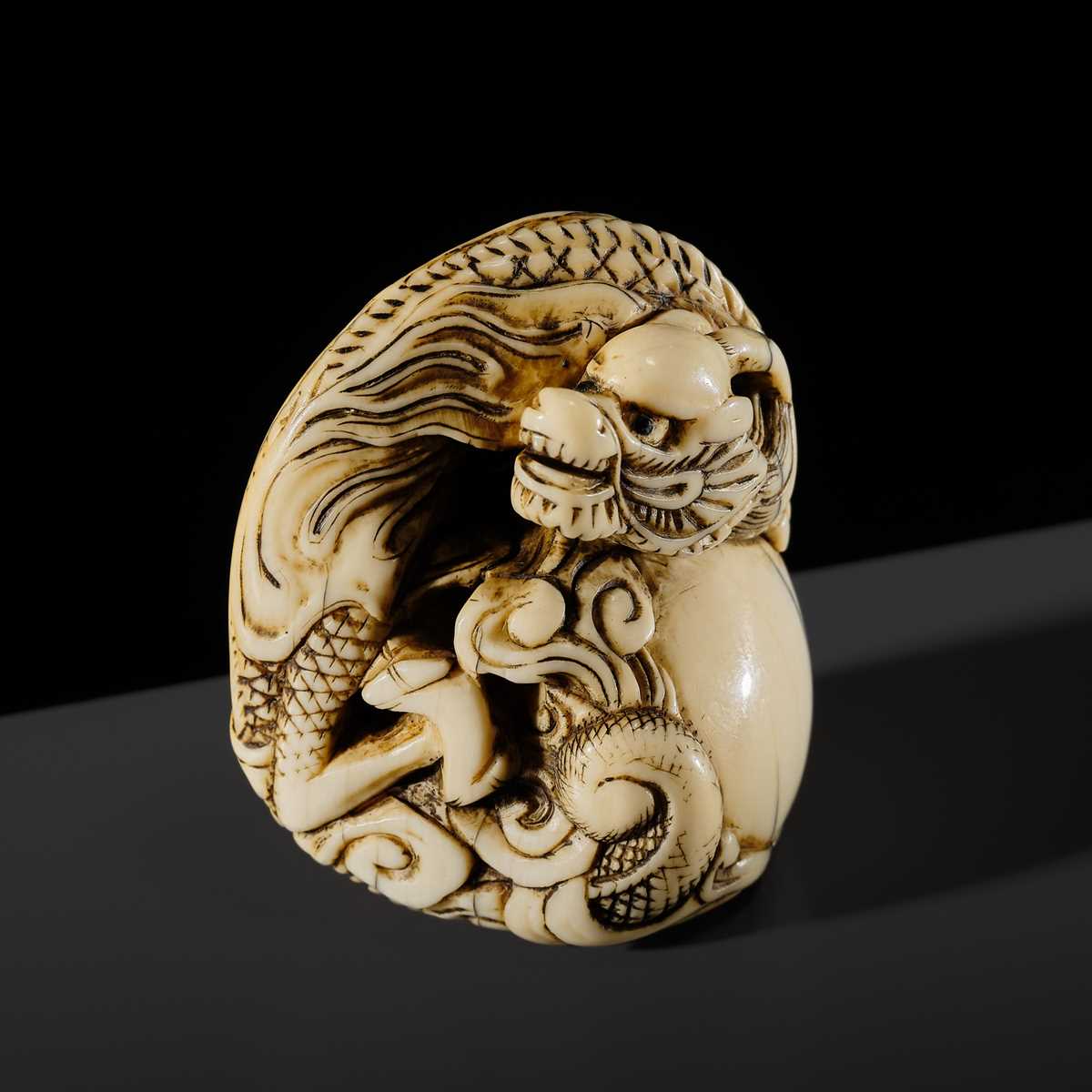 Lot 114 - A POWERFUL KYOTO SCHOOL IVORY NETSUKE OF A DRAGON AND TAMA PEARL
