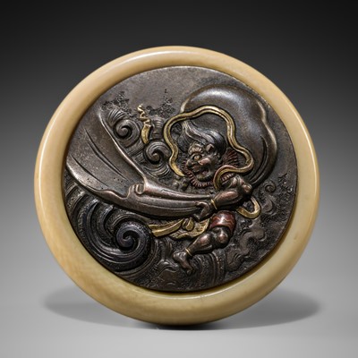 AN IVORY AND SHIBUICHI KAGAMIBUTA NETSUKE DEPICTING FUJIN