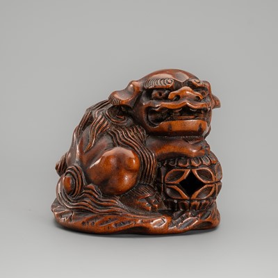 MINKOKU: A WOOD NETSUKE OF A SHISHI WITH BALL
