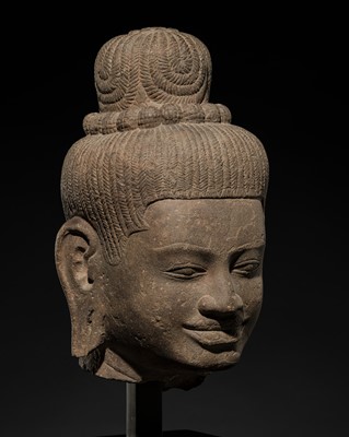 Lot 261 - A RARE AND IMPORTANT OVER-LIFESIZE SANDSTONE HEAD OF A FEMALE DEITY, ANGKOR PERIOD, BAPHUON STYLE
