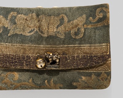 Lot 332 - A LEATHER TABAKO-IRE (POUCH) WITH A KANAMONO (CLASP) DEPICTING A SHISHI AND SUZU BELL, STYLE OF OZAKI KOKUSAI