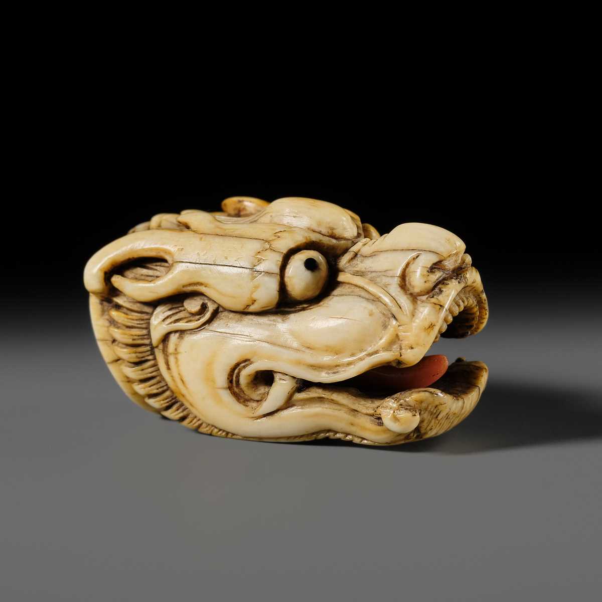 Lot 113 - A VERY RARE CORAL INLAID IVORY NETSUKE OF A SEVERED DRAGON HEAD