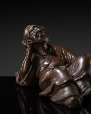Lot 357 - A BRONZE BRUSH REST IN FROM OF A RECLINING SCHOLAR, 17TH CENTURY