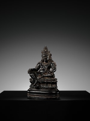 Lot 20 - A FINELY CARVED BLACK STONE FIGURE OF JAMBHALA, TIBET, 15TH-17TH CENTURY