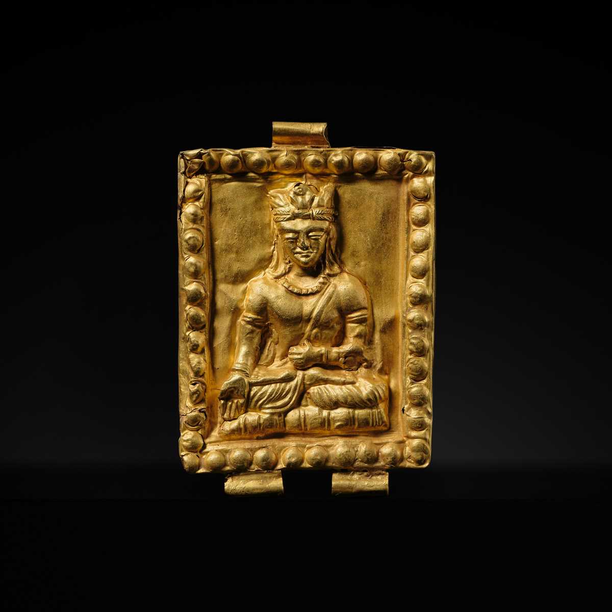 Lot 98 - A GOLD REPOUSSÉ ‘CROWNED BUDDHA’ PENDANT, ANCIENT REGION OF GANDHARA