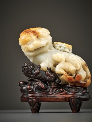 Lot 67 - A RUSSET AND WHITE JADE ‘BUDDHIST LION’ WATER POT AND COVER WITH MATCHING HARDWOOD BASE, LATE MING TO EARLY QING