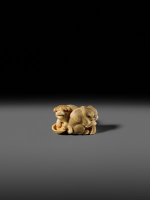 Lot 121 - OKATOMO: A CHARMING IVORY NETSUKE OF TWO PUPPIES WITH AWABI