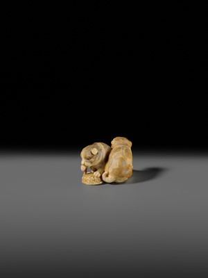 Lot 121 - OKATOMO: A CHARMING IVORY NETSUKE OF TWO PUPPIES WITH AWABI
