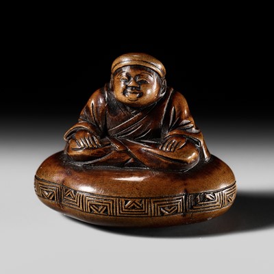 A FINE WOOD NETSUKE OF A MAN SEATED ON A CUSHION