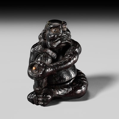 A FINE INLAID EBONY WOOD NETSUKE OF AN ONI APPLYING MOXA, ATTRIBUTED TO MIWA