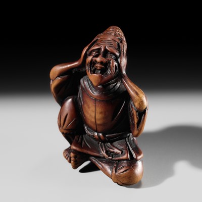 Lot 484 - JUSEI: A HUMOROUS WOOD NETSUKE OF A COURT NOBLE SITTING ON A MOXA PELLET