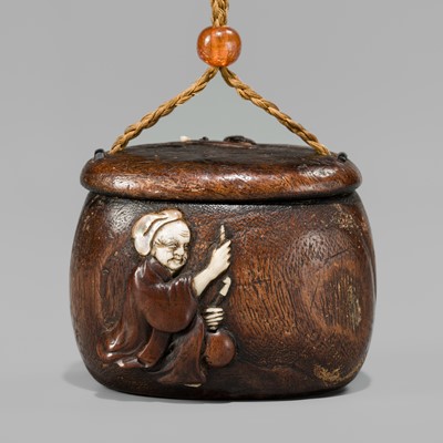 Lot 394 - TANAKA MINKO: AN INLAID WOOD TONKOTSU WITH A RAOYA CLEANING A SMOKING PIPE (KISERU)