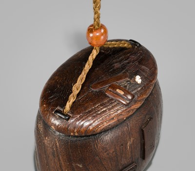 Lot 394 - TANAKA MINKO: AN INLAID WOOD TONKOTSU WITH A RAOYA CLEANING A SMOKING PIPE (KISERU)