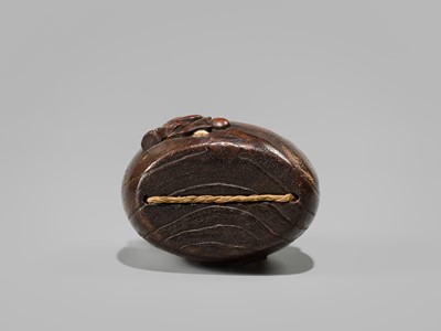 Lot 394 - TANAKA MINKO: AN INLAID WOOD TONKOTSU WITH A RAOYA CLEANING A SMOKING PIPE (KISERU)