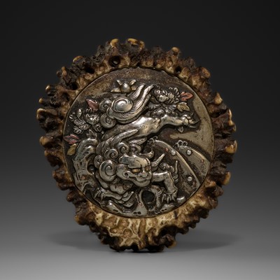 Lot 526 - A LARGE SILVER INLAID ANTLER KAGAMIBUTA NETSUKE DEPICTING A SHISHI AMONG PEONIES