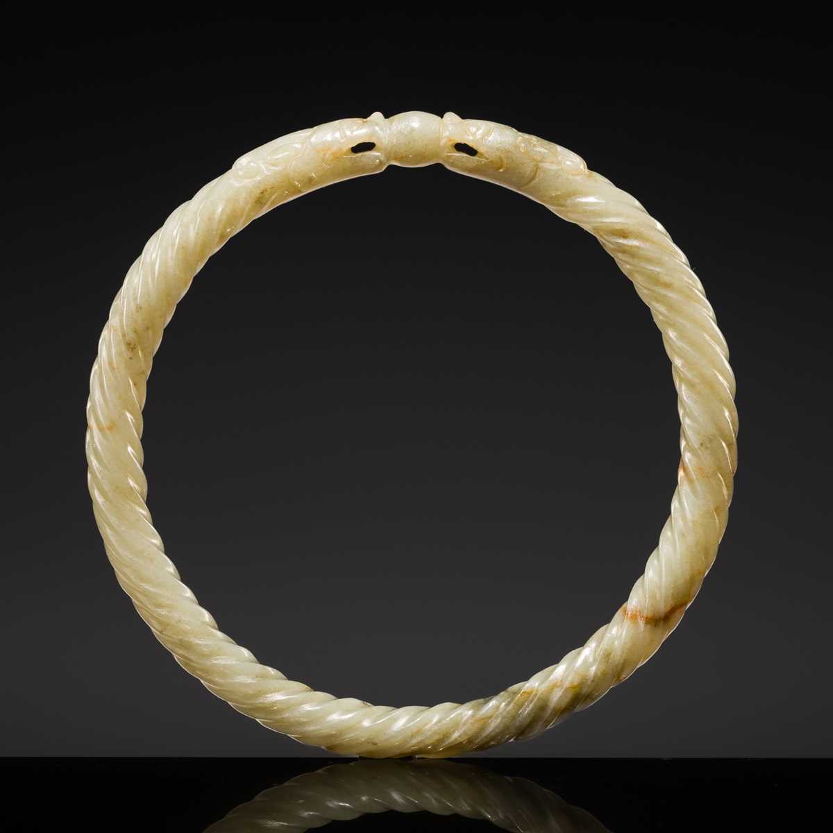 A DELICATE CELADON AND BROWN ’DRAGON’ JADE ROPE-TWIST BANGLE, QING DYNASTY
