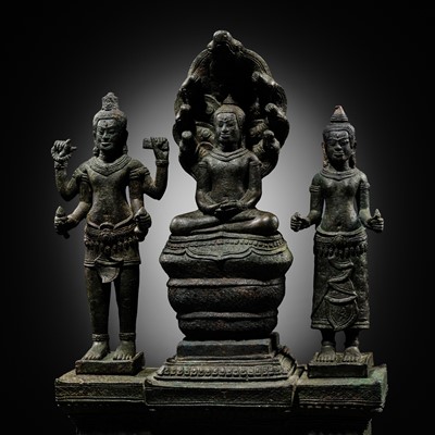 Lot 443 - A BUDDHIST BRONZE TRIAD OF BUDDHA MUCHALINDA WITH HIS CONSORTS LOKESHVARA AND PRAJNAPARAMITA, BAYON STYLE, 13TH CENTURY