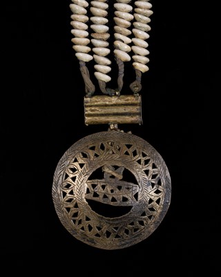 Lot 180 - A COWRIE SHELL AND BRASS ‘MANDALA’ DODCHA (BELT ORNAMENT), EARLY 20TH CENTURY