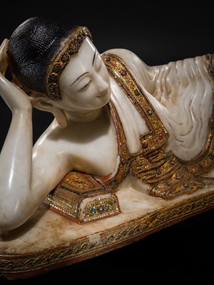 Lot 15 - A LARGE GLASS INLAID AND GILDED ALABASTER FIGURE OF THE RECLINING BUDDHA, MANDALAY PERIOD, 19TH CENTURY