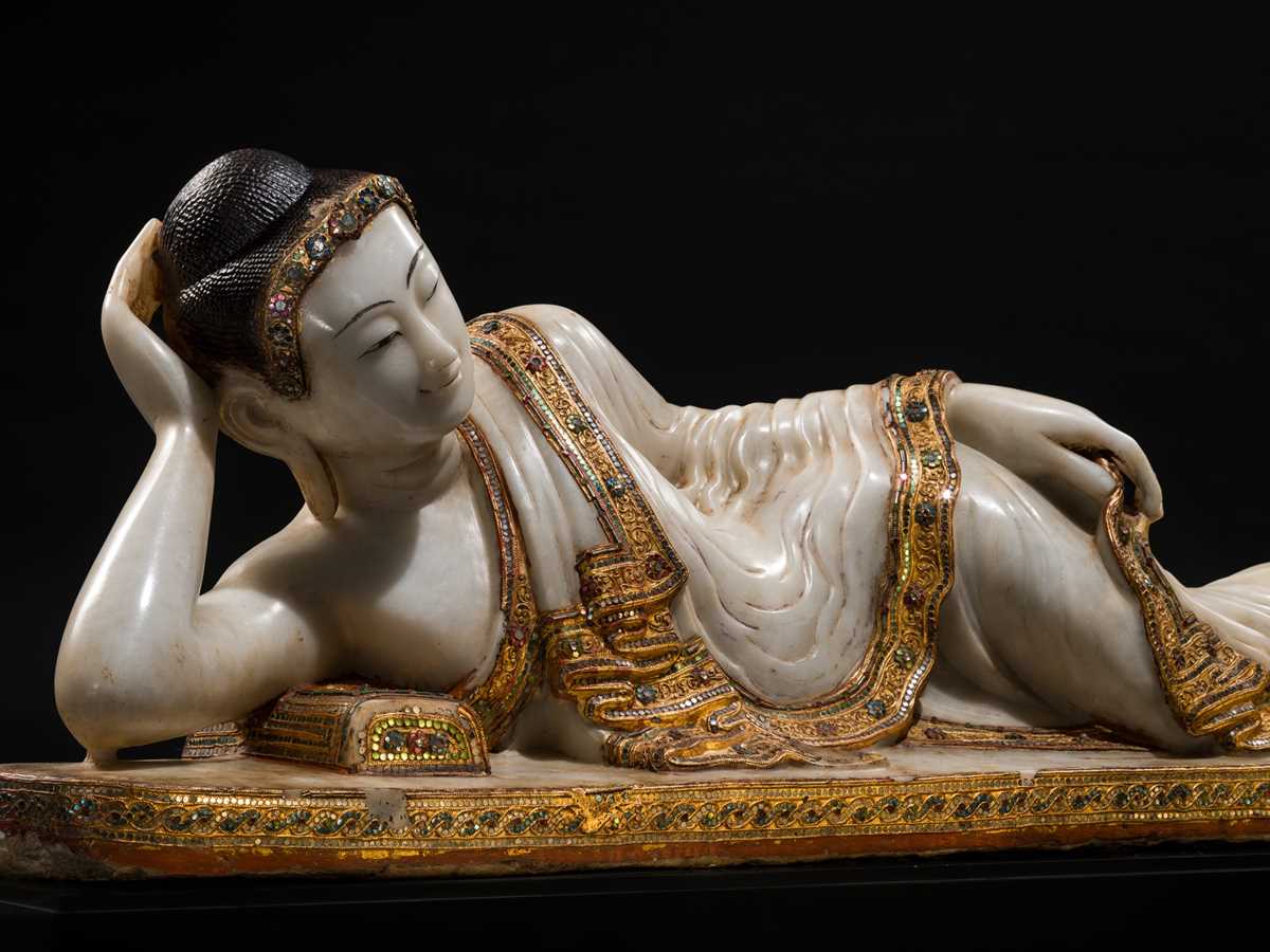 Lot 15 - A LARGE GLASS INLAID AND GILDED ALABASTER FIGURE OF THE RECLINING BUDDHA, MANDALAY PERIOD, 19TH CENTURY