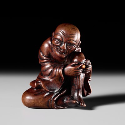 ANRAKU: A GOOD WOOD NETSUKE OF A MAN APPLYING MOXA
