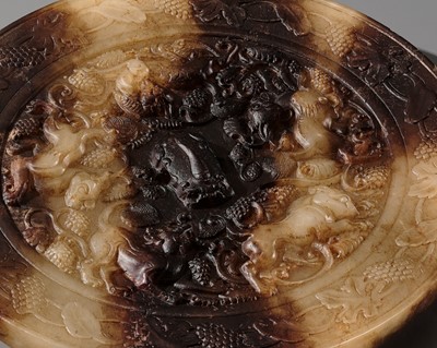 Lot 123 - A VERY RARE YELLOW AND BROWN JADE ‘LION AND GRAPEVINE’ MIRROR, QING DYNASTY OR EARLIER