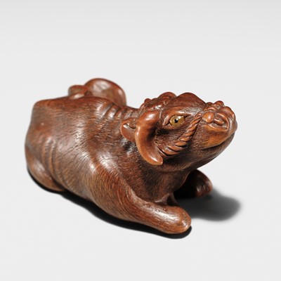 HARUMITSU: A SUPERB WOOD NETSUKE OF A RECUMBENT OX