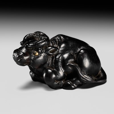 KOKEI: AN EBONY WOOD NETSUKE OF A RECUMBENT OX