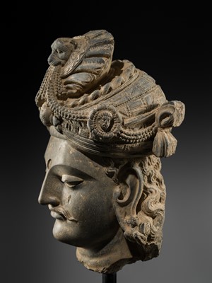 Lot 248 - A LARGE SCHIST HEAD OF A BODHISATTVA WITH A ‘KĪRTIMUKHA’ TURBAN, GANDHARA, 4TH–5TH CENTURY, FORMERLY IN THE COLLECTION OF BEGUM BAKHT ZEBA