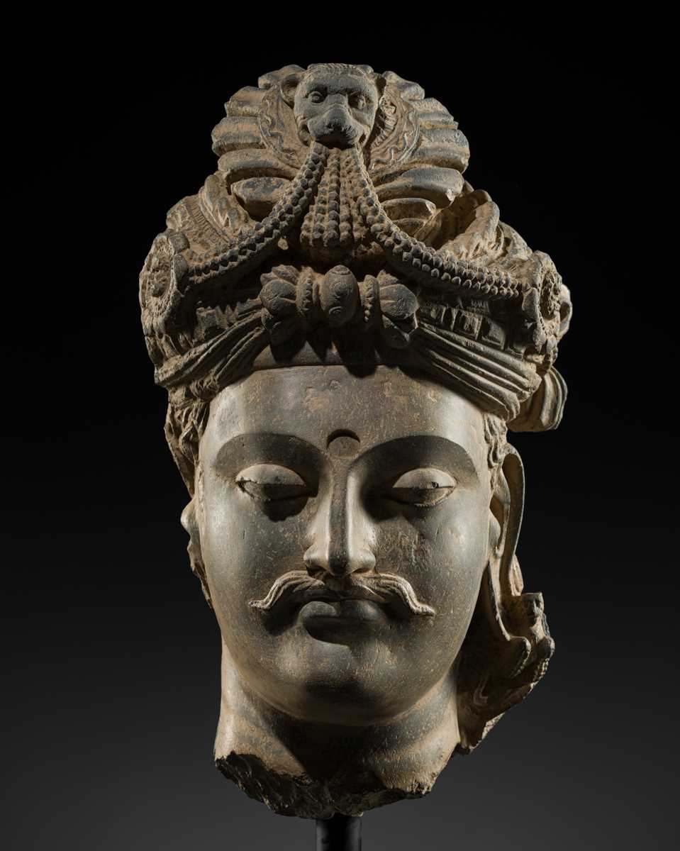 Lot 248 - A LARGE SCHIST HEAD OF A BODHISATTVA WITH A ‘KĪRTIMUKHA’ TURBAN, GANDHARA, 4TH–5TH CENTURY, FORMERLY IN THE COLLECTION OF BEGUM BAKHT ZEBA