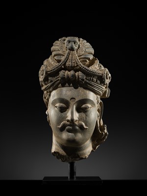 Lot 248 - A LARGE SCHIST HEAD OF A BODHISATTVA WITH A ‘KĪRTIMUKHA’ TURBAN, GANDHARA, 4TH–5TH CENTURY, FORMERLY IN THE COLLECTION OF BEGUM BAKHT ZEBA