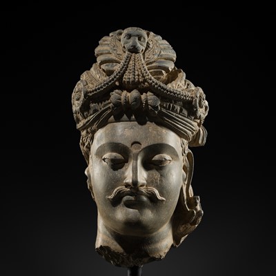 Lot 248 - A LARGE SCHIST HEAD OF A BODHISATTVA WITH A ‘KĪRTIMUKHA’ TURBAN, GANDHARA, 4TH–5TH CENTURY, FORMERLY IN THE COLLECTION OF BEGUM BAKHT ZEBA