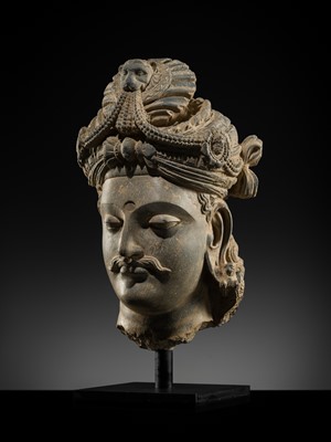 Lot 248 - A LARGE SCHIST HEAD OF A BODHISATTVA WITH A ‘KĪRTIMUKHA’ TURBAN, GANDHARA, 4TH–5TH CENTURY, FORMERLY IN THE COLLECTION OF BEGUM BAKHT ZEBA